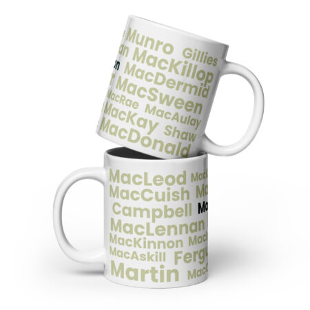 Certainly. Here is a factual description: The Mug - Morrison features a white exterior decorated with various Scottish surnames, including Morrison, presented in large light green and black text. The image depicts two mugs stacked one atop the other.