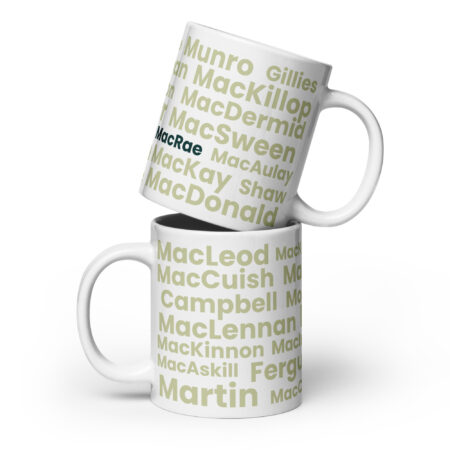 Two white mugs, identified as Mug - MacRae, are stacked together. Each mug displays several Scottish surnames in light green text. The surname MacRae is prominently highlighted in black and blue on each mug.