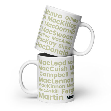 Two white Mug - MacCusbic mugs are stacked. Each mug features bold green and gray Scottish surnames—MacLeod, MacDonald, Munro, and MacCusbic—set against a clean white background.
