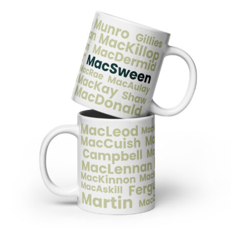 Understood. Here is a factual description: Two white Mug - MacSween mugs are stacked together against a white background. Each mug features the word MacSween printed in bold black text. The design and color of both mugs are identical, with no additional decorations or patterns visible.