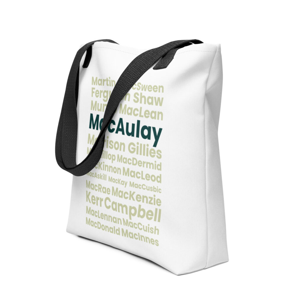 The Tote bag - MacAulay is a white tote bag featuring black handles. Its design includes numerous Scottish surnames printed in green text. Among these, MacAulay and Kerr Campbell are printed in a larger, bold font to make them stand out from the other names.