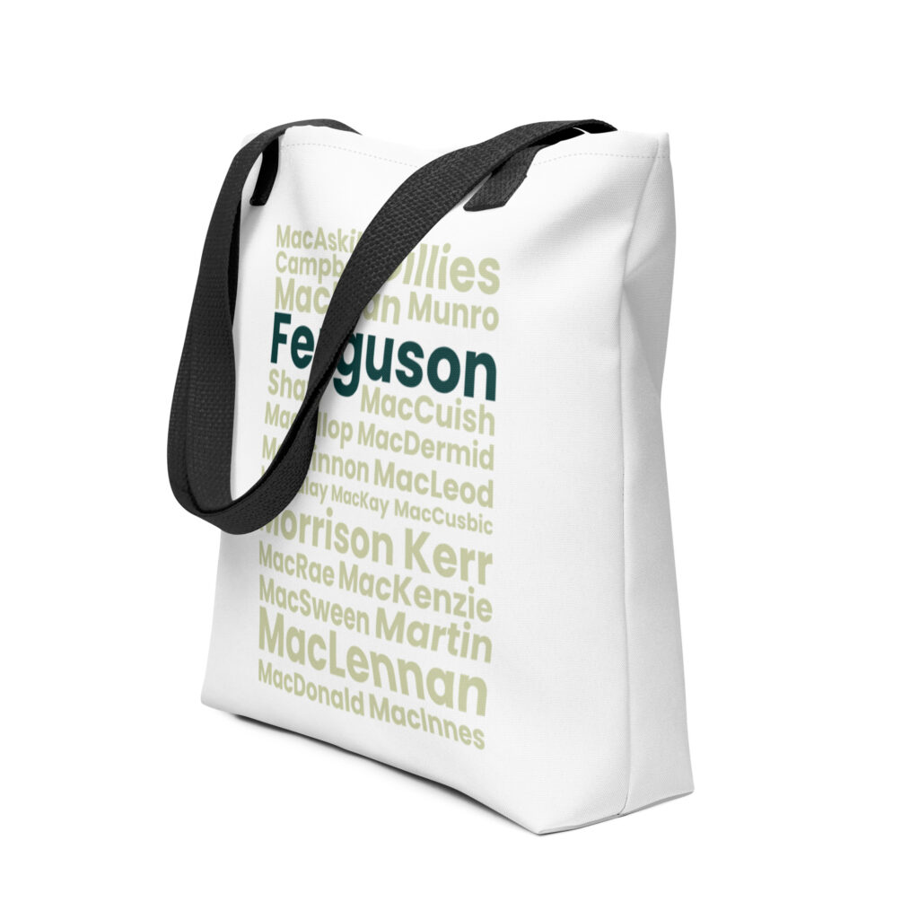 Understood. Here is a factual description: The Tote bag - Ferguson is a white tote bag with black handles. The design features a cluster of Scottish surnames printed in various shades of green, with the surname Ferguson prominently highlighted at the center.