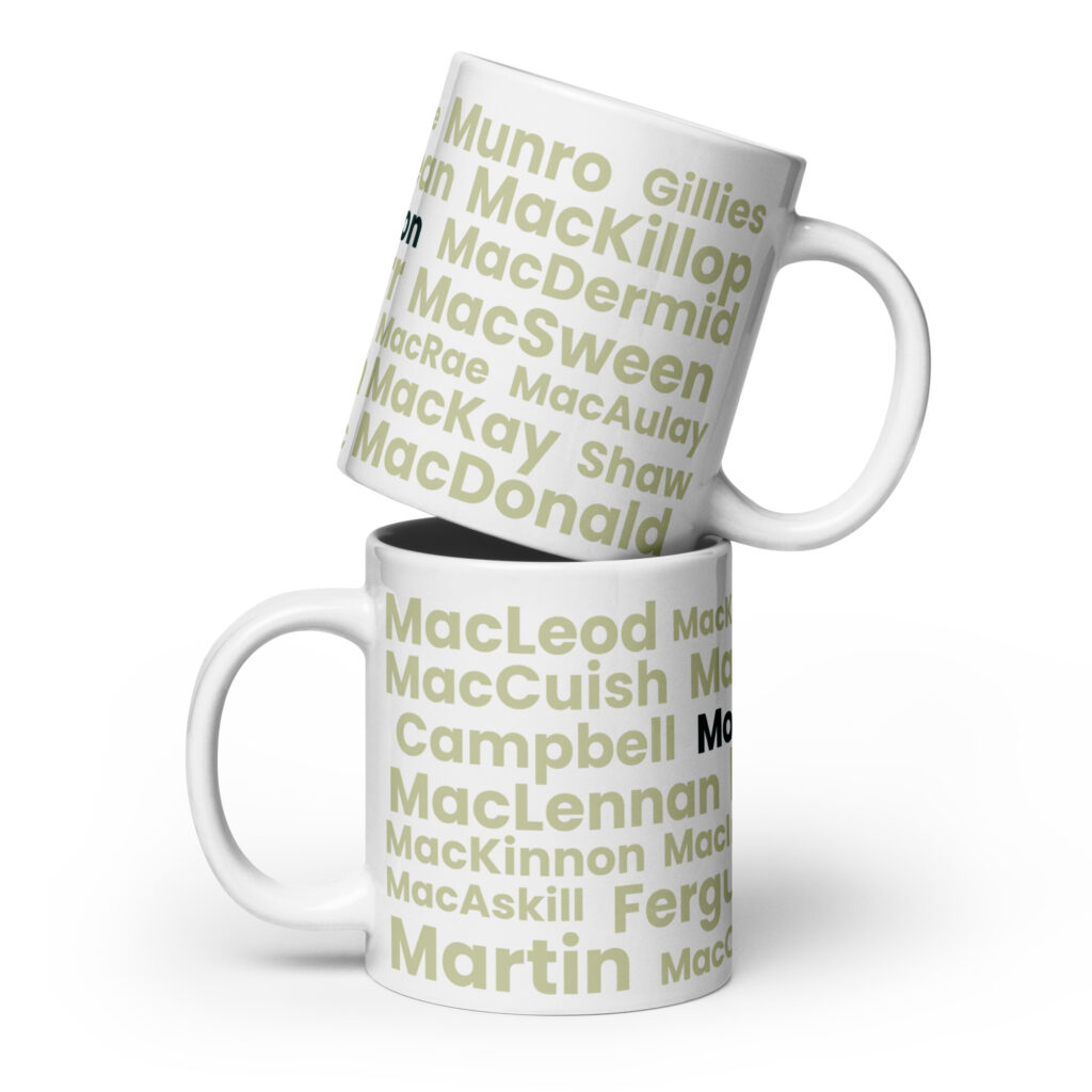 Certainly. Here is a factual description: The Mug - Morrison features a white exterior decorated with various Scottish surnames, including Morrison, presented in large light green and black text. The image depicts two mugs stacked one atop the other.