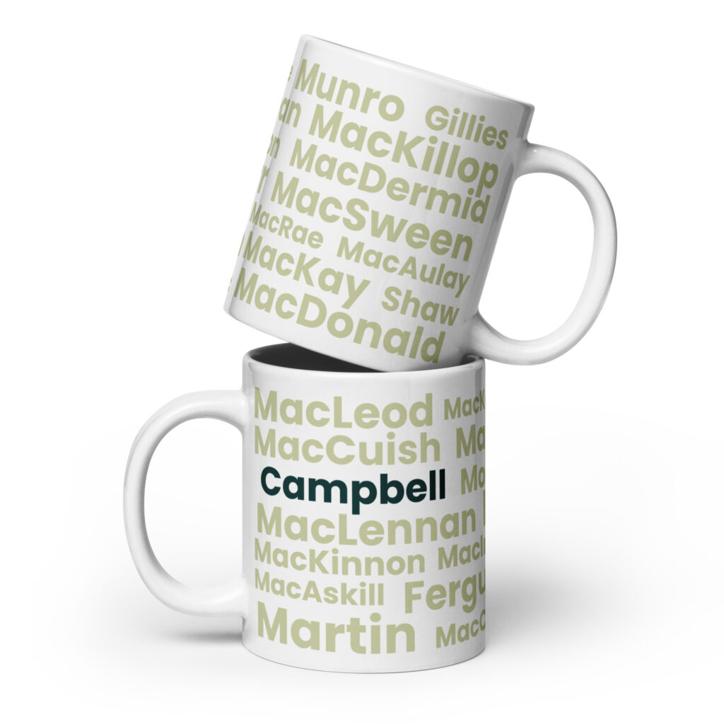 Two white mugs feature Scottish surnames in green and beige text. The bottom mug displays a bold Campbell design. One mug is stacked on top of the other.
