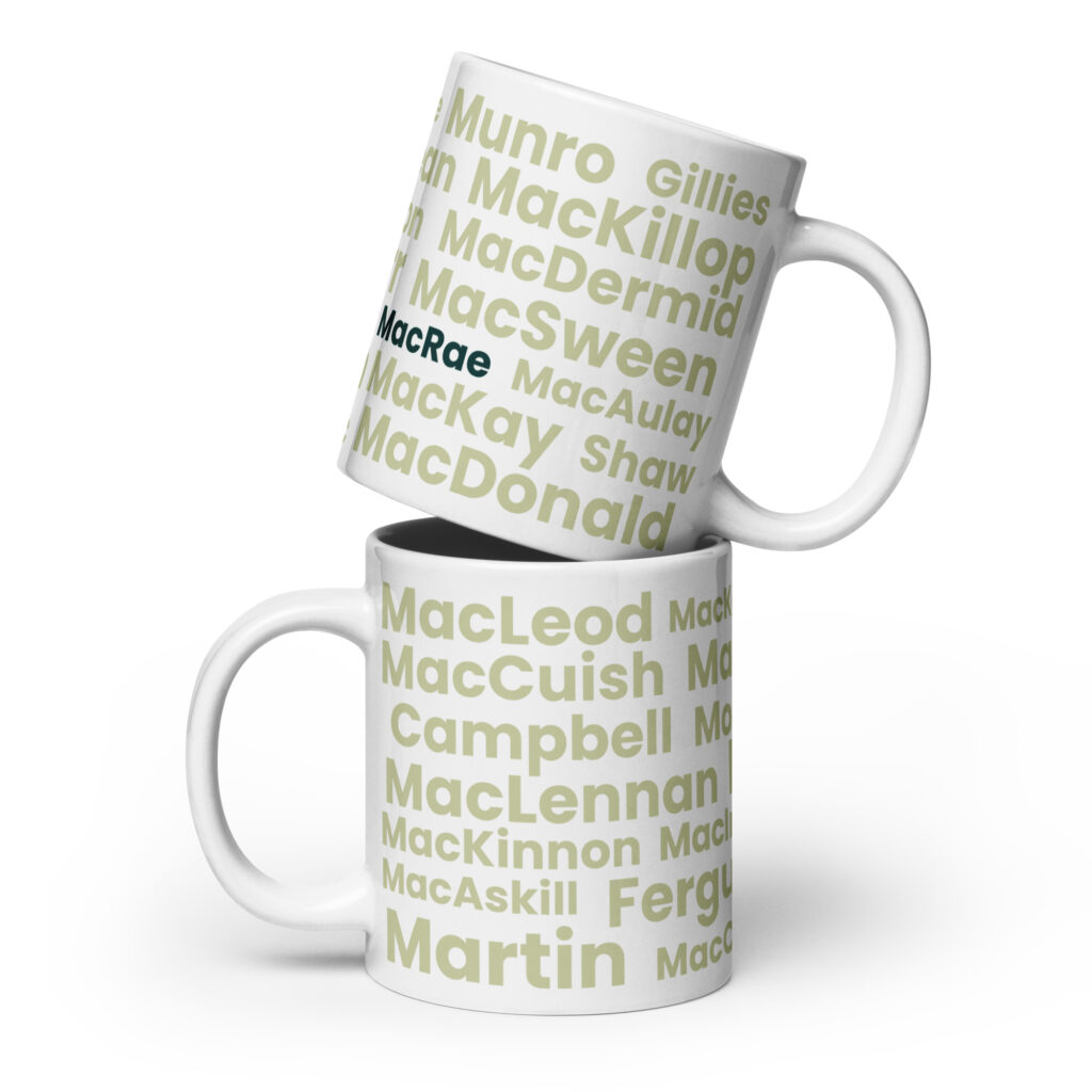 Two white mugs, identified as Mug - MacRae, are stacked together. Each mug displays several Scottish surnames in light green text. The surname MacRae is prominently highlighted in black and blue on each mug.
