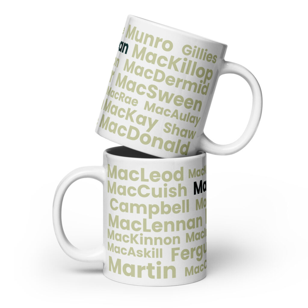 Two white mugs labeled Mug - MacLean are stacked. Each mug features a green and gray pattern displaying various Scottish surnames, including MacLean. The background is plain white.